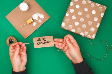 Bir Noel hediyesi Kraft kağıt, beyaz boya, patates bir damga özgün tasarım. Adım adım resmi için. El yapımı, DIY. Beyaz lekeli ile kahverengi kağıt sarılı bir hediye