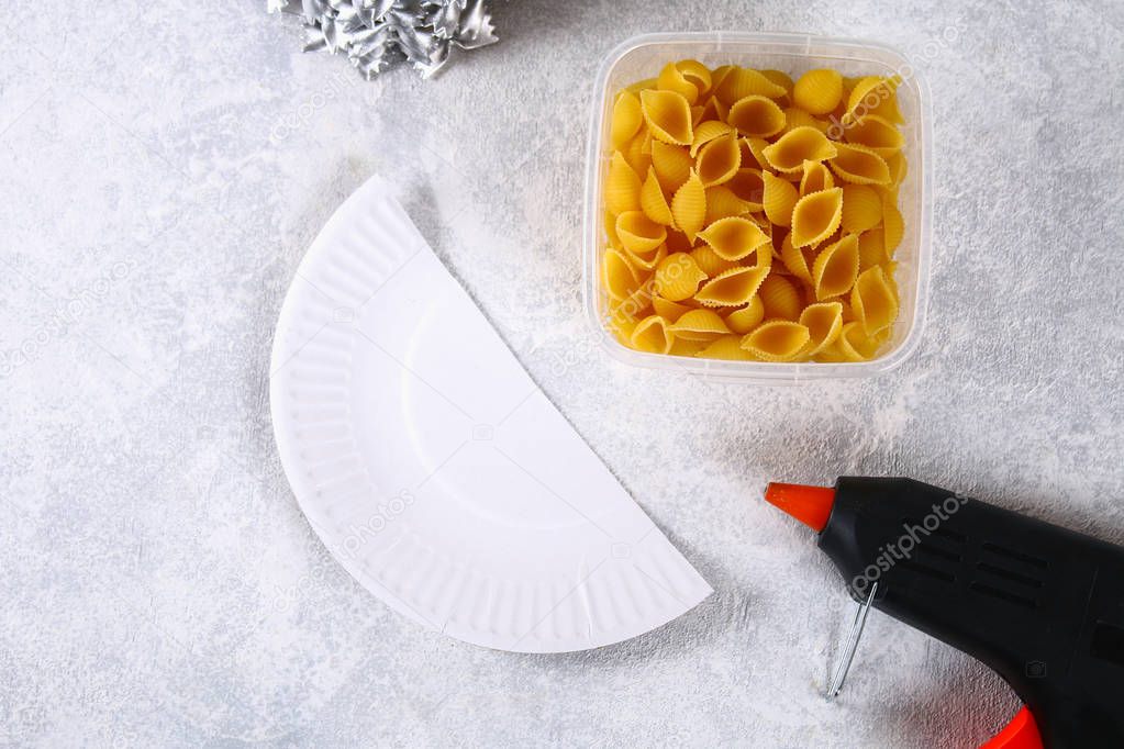 How to make a Christmas tree from raw pasta conchiglie. The process of making Christmas trees from pasta, cardboard plates, hot glue and paint or spray. Guide, step by step on the photo. Handmade, DIY