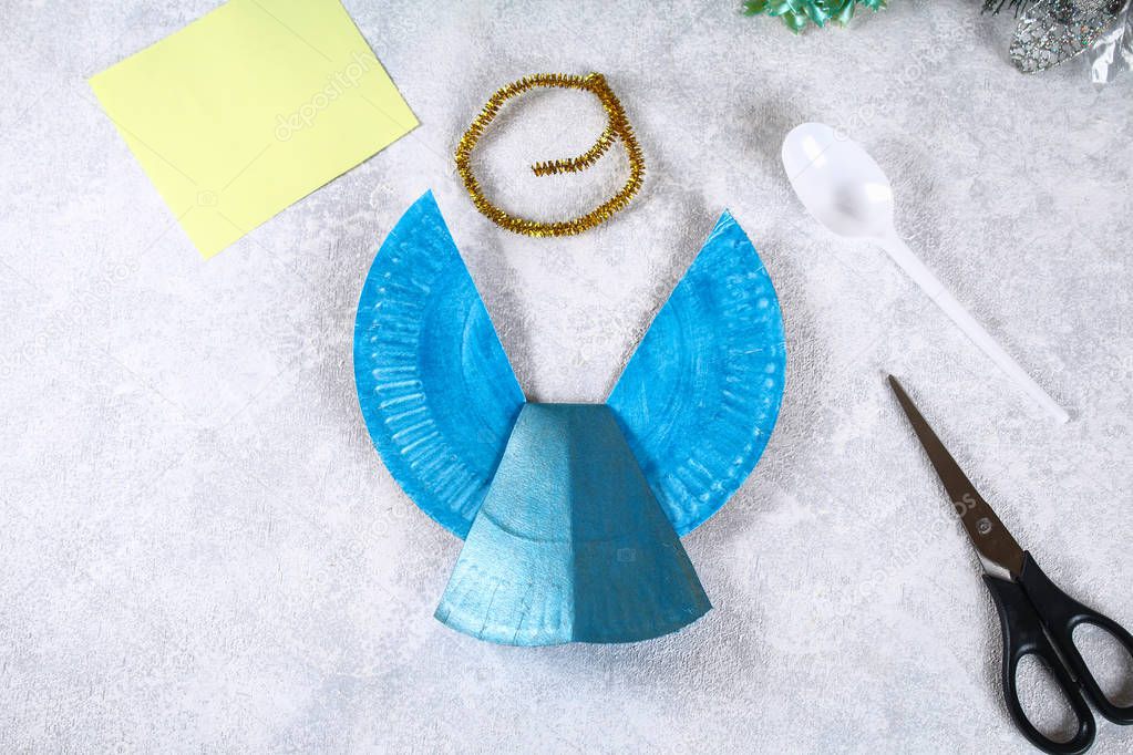 The process of creating your own Christmas angel from a disposable cardboard plate, a plastic spoon and paper. Christmas decor. Handmade, hobby, DIY