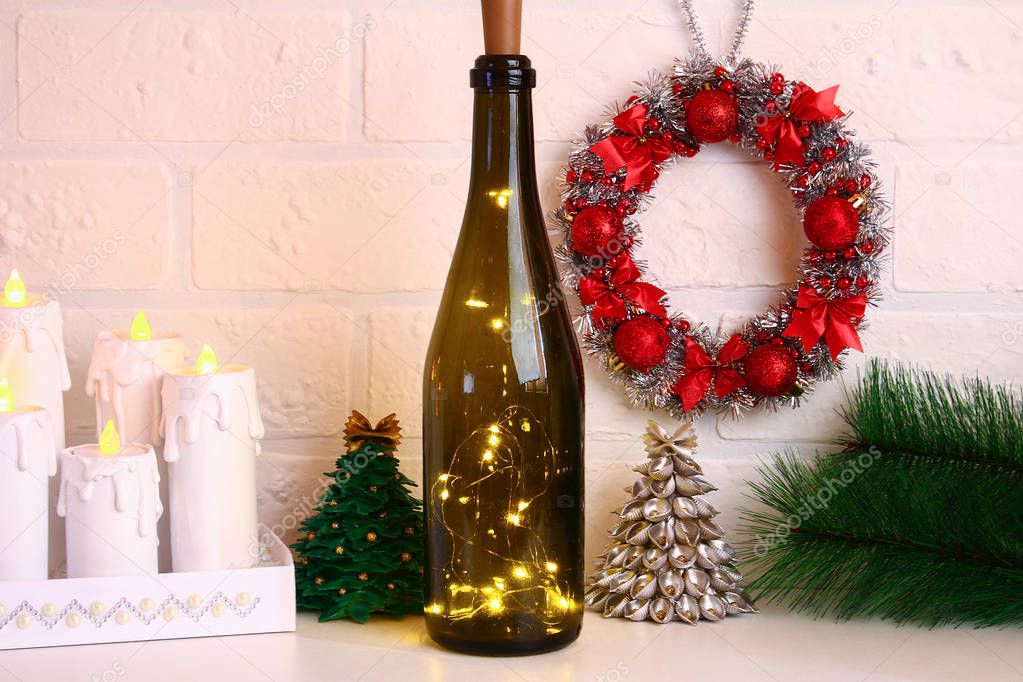 Garland in the bottle. Empty champagne bottle with garland inside on white table. Glowing decor for Christmas. Diy, handmade with their own hands.