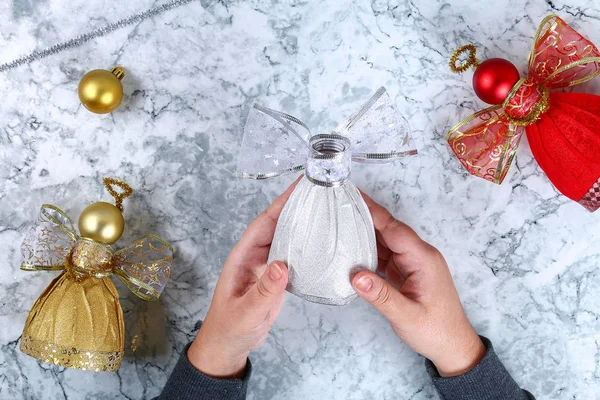 Diy Angel plastic bottle. Guide on the photo how to make a decorative angel from a bottle, self-adhesive shiny paper, ribbon and a Christmas ball with your own hands. Handmade. Top view. Step by step.