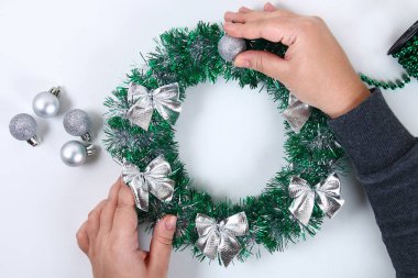 DIY Noel çelenk. Fotoğrafta bir plastik tabak, tinsel, boncuk, yay ve topları kendi elleriyle bir Noel çelenk yapmak nasıl Kılavuzu. El yapımı dekor. Gümüş yeşil çelenk. Üstten görünüm
