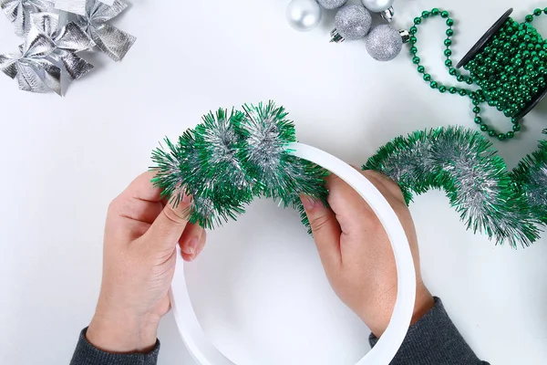 Diy Christmas wreath. Guide on the photo how to make a Christmas wreath with your own hands from a plastic plate, tinsel, beads, bows and balls. Handmade The decor. Silver green wreath. Top view