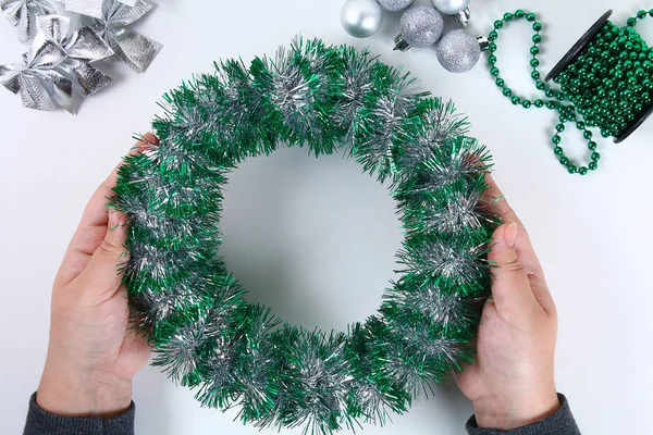 Diy Christmas wreath. Guide on the photo how to make a Christmas wreath with your own hands from a plastic plate, tinsel, beads, bows and balls. Handmade The decor. Silver green wreath. Top view