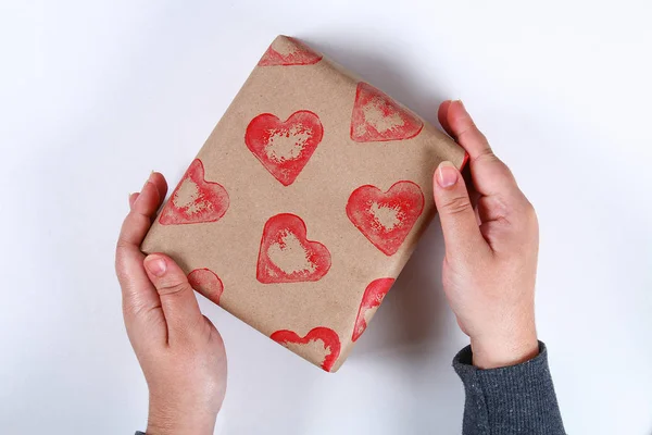 Diy. Gift wrapping for Valentine\'s Day. Kraft paper gift and potato stamp in the shape heart and red paint do it yourself on February 14th. Top view on a white background. step by step. Handicraft