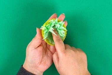 Paskalya DIY tavşan yeşil arka plan üzerinde yumurta. Hediye fikirleri, dekorasyon Paskalya, bahar. El yapımı. Beyaz Paskalya yortusu yumurta bunny, çim peçete, silikon fincan kek kek. Adım adım. İşlem el sanatları. Üstten görünüm.