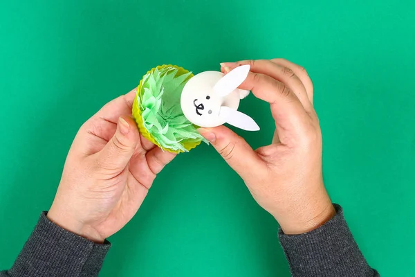 从绿色背景上的复活节蛋中得到的多兔子 礼物的想法 装饰复活节 白复活节蛋兔子 草餐巾 硅胶杯松饼蛋糕 一步一步 工艺工艺 顶视图 — 图库照片