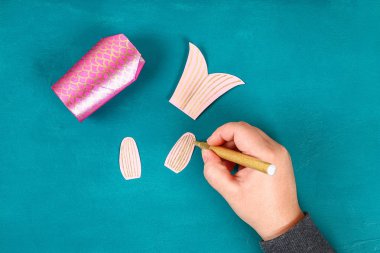 Mavi yeşil arka planda Diy koi sazan balığı. Çin yeni yılı için hediye fikirleri, dekor. Çocuk el yapımı. Sazan balığı kağıdı, tuvalet kağıdı, şaşı gözler. Adım adım. Çocuk işçiliğini işleyin. Üst görünüm.