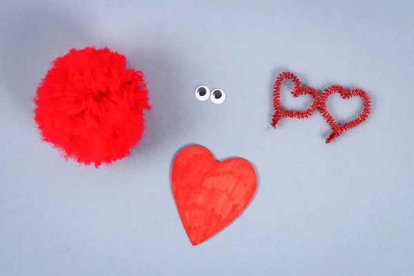 Red handmade diy monster pom pom from yarn, chenille stems in shape heart. Gift ideas for Valentines Day, day of love, the concept of February 14. Step by step. Process of kid crafts. Top view.