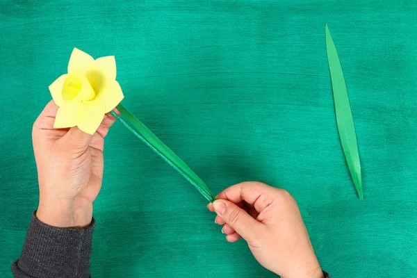 染春花水仙花的黄纸上有绿色的背景 礼物的想法 春天的装饰 复活节 一步一步 工艺的过程 顶部视图 儿童复活节工艺品 — 图库照片