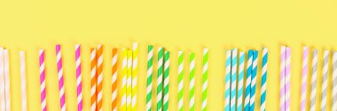 Afiş. Çok renkli saman kağıt tüpler parlak sarı pastel arka plan üzerinde. Üstten görünüm, kopya alanı