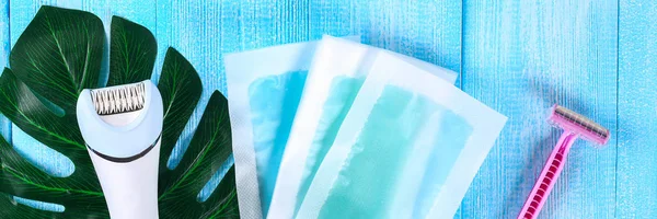 毛の取り外しのための手段 脱毛器は かみそりのシェービング ワックス ストリップ青い木製の背景に熱帯の葉の上 シェービング — ストック写真