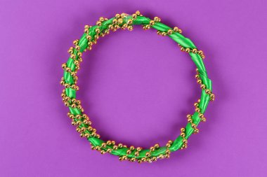DIY çelenk Mardi Gras, Fat Salı mor arka plan. Hediye fikri, dekor Mardi Gras. Çelenk plastik tabaklar, saten kurdele, yeşil, sarı, mor boncuk. Adım adım. İşlem çocuk zanaat. Üstten görünüm.