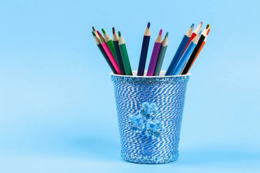DIY kalem tutucu plastik bardak ekşi krema, yoğurt iplik mavi arka plan sarılmış. Dekorasyon çiçek sıcak tutkal, dekoratif yapışkan bant. Hediye fikri. Adım adım. Üstten görünüm. Süreci çocuk çocuk zanaat