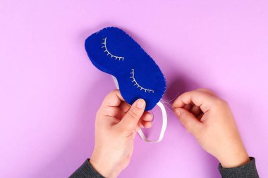 DIY mavi beyaz iplik kirpik sakız mor arka planda üzerinde kapalı gözlerle işlemeli ile uyku maskesi hissettim. Dikiş, dikiş. Hediye fikri, dekor. Adım adım. Üstten görünüm. Uykusuzluk.
