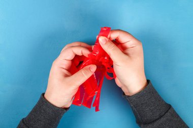 DIY Paskalya yortusu yumurta basket kırmızı plastik bardak made yapay çiçekler mavi arka plan ile dekore edilmiştir. Hediye fikri, dekor bahar, Paskalya. Adım adım. Üstten görünüm. Çocuk Çocuk Paskalya zanaat işlemek. geri dönüşüm