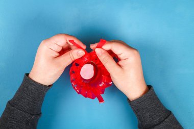 DIY Paskalya yortusu yumurta basket kırmızı plastik bardak made yapay çiçekler mavi arka plan ile dekore edilmiştir. Hediye fikri, dekor bahar, Paskalya. Adım adım. Üstten görünüm. Çocuk Çocuk Paskalya zanaat işlemek. geri dönüşüm