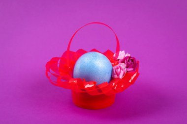 DIY Paskalya yortusu yumurta sepet kırmızı plastik bardak yapılan yapay çiçekler mor arka plan ile dekore edilmiştir. Hediye fikri, dekor bahar, Paskalya. Çocuk Çocuk Paskalya zanaat işlemek. geri dönüşüm