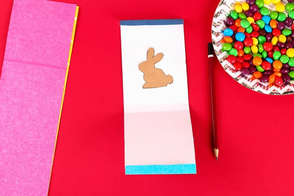 Diy Osterverpackung Süßigkeiten in einer Tüte mit einem ausgeschnittenen Häschen Silhouette auf rotem Hintergrund. — Stockfoto