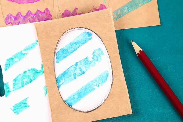 Diy Easter eggs made of cardboard and potato stamp, Easter greeting card on green background.
