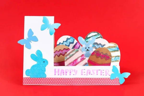Diy Easter eggs made of cardboard and potato stamp, Easter greeting card on red background.