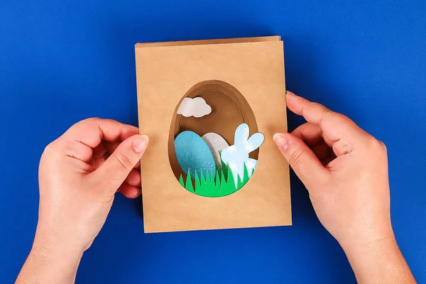 Diy tarjetas de Pascua de papel. Volumen tarjetas de felicitación con un conejo, huevo sobre fondo azul. 3d . — Foto de Stock