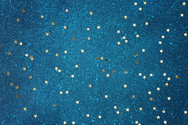 Konfetti in Form von Goldsternen auf blauem Grund. sternenblauer Himmel Hintergrund. — Stockfoto