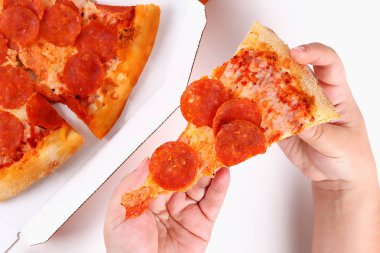 Bir kız beyaz arka planda pepperoni pizza bir dilim tutar. Üst görünüm.
