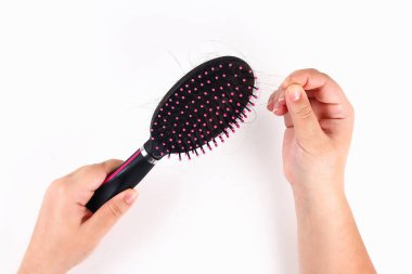 Kız beyaz bir arka planda bir tarak ve kayıp saç tutar. Üst görünüm.