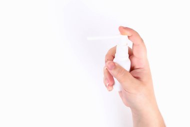 Kız beyaz arka planda elinde bir boğaz spreyi tutuyor. Üst görünüm.