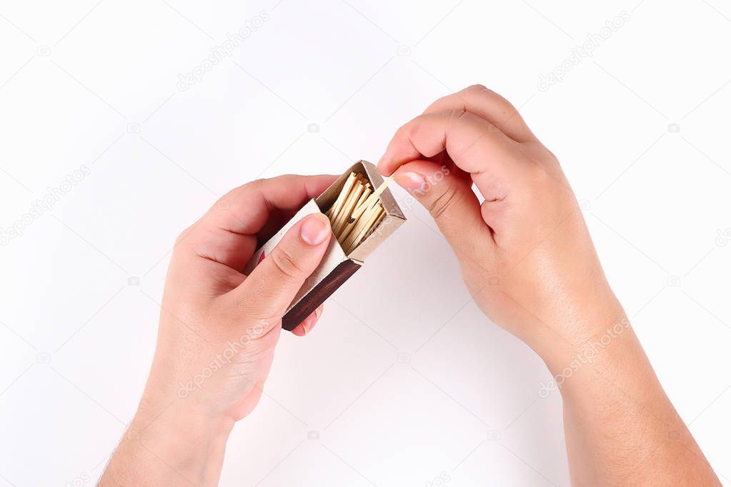 The girl lights a match from a box of matches on white background. Top view.