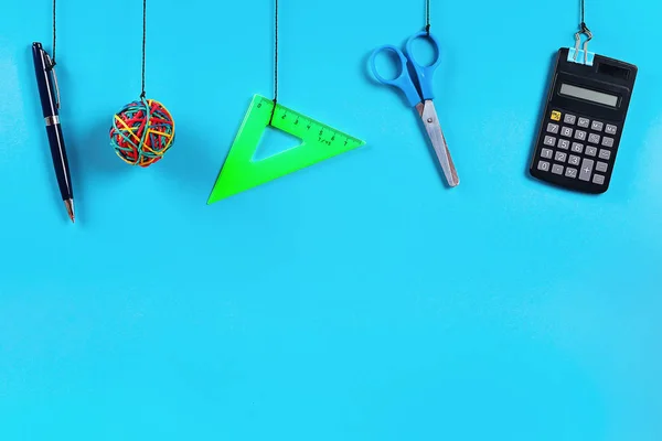 Los útiles escolares cuelgan de la cuerda. Material escolar sobre fondo azul —  Fotos de Stock