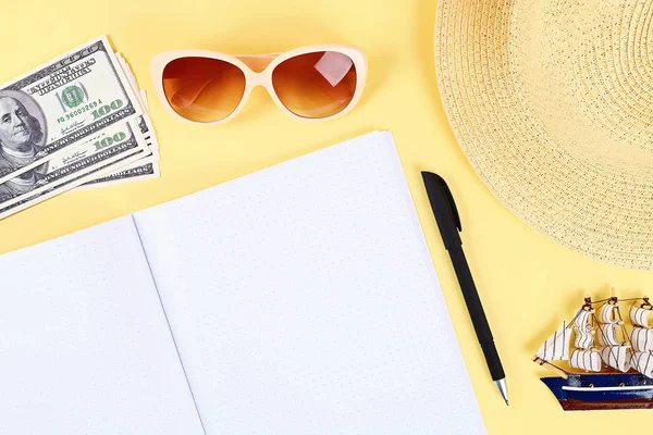 Bloc de notas fondo amarillo, gafas de sol, sombrero, dinero. Espacio superior view.copy. Fondo de verano, viajes . — Foto de Stock