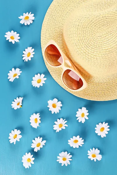 Sombrero de paja y gafas de sol con manzanilla sobre fondo azul. Vista superior. Fondo de verano. Puesta plana . — Foto de Stock