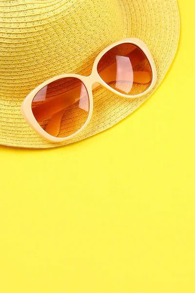 Cappello, occhiali da sole su sfondo giallo pastello . — Foto Stock