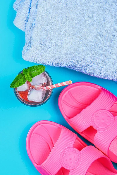Zapatillas, una toalla y un cóctel de hielo sobre un fondo azul pastel. Descanso, viaje . — Foto de Stock