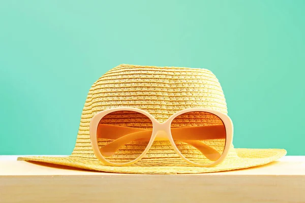Gafas de sol amarillas y sombrero en un estante de madera sobre un fondo pastel de menta. Minimalismo . — Foto de Stock