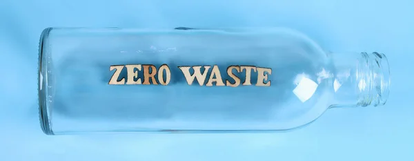 Zero waste concept. Empty glass bottle for zero waste shopping and storage on blue background