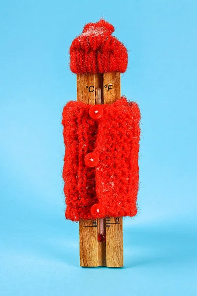 木制温度计,戴着红色帽子,穿着蓝色背景的毛衣 — 图库照片
