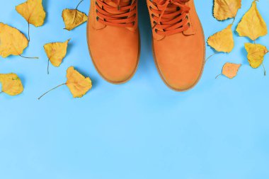 Mavi pastel arka plan turuncu kahverengi erkek sonbahar botları. Üst görünüm, kopyalama alanı.
