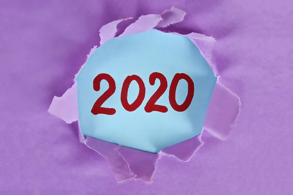 Sönderrivna pjäs papper avslöjar ordet nyår 2020. Jul koncept. Nytt år hyvning. 2020 mål. — Stockfoto
