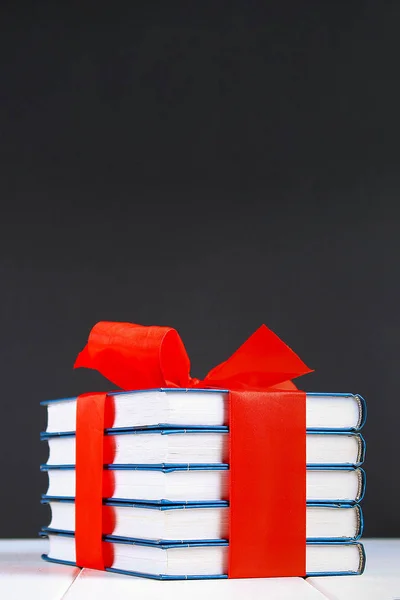 Ένας σωρός από βιβλία δεμένα με μια κόκκινη κορδέλα σε ένα λευκό ξύλινο τραπέζι. — Φωτογραφία Αρχείου
