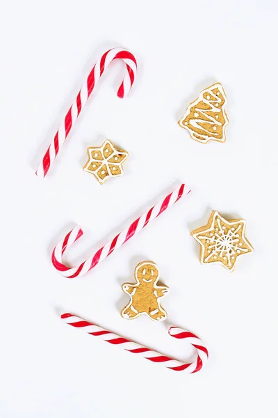 Diseño navideño. Caramelos de caña rojo-blanco rayados y galletas de jengibre caseras sobre un fondo blanco — Foto de Stock