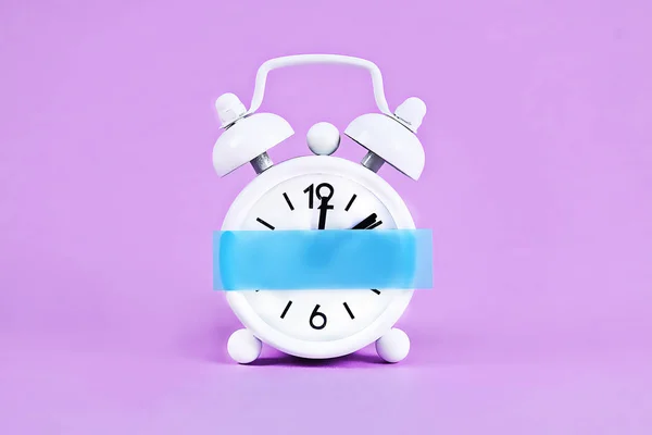 Reloj despertador blanco violeta fondo pastel. Nota pegajosa en blanco en el reloj. Copia espacial. Concepto mínimo . —  Fotos de Stock