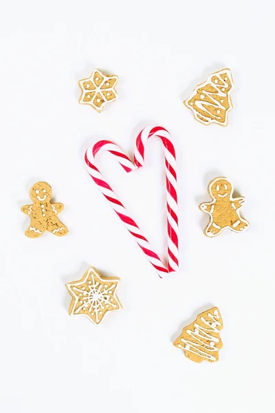 Diseño navideño. Caramelos de caña rojo-blanco rayados y galletas de jengibre caseras sobre un fondo blanco — Foto de Stock