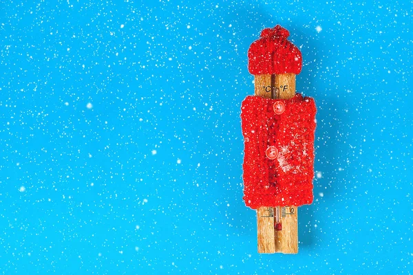 Деревянный термометр, в красной шляпе и свитере на синем фоне — стоковое фото