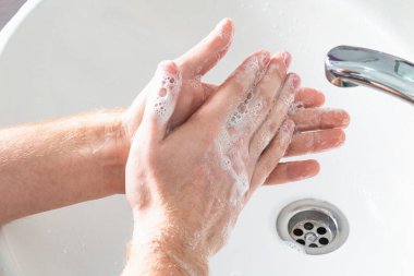 Adam su altında sabun ve ellerini yıkıyor. Hijyen konsepti el detayı.