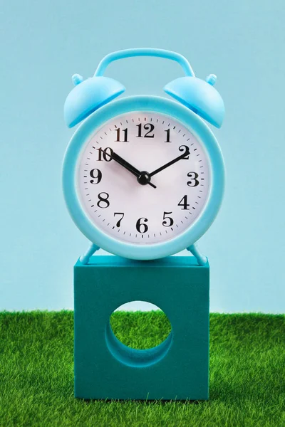 Relógio despertador na grama ou gramado fundo - conceito de tempo . — Fotografia de Stock