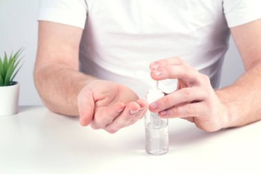 Küçük portatif antibakteriyel el dezenfektanı kullanan bir adam..