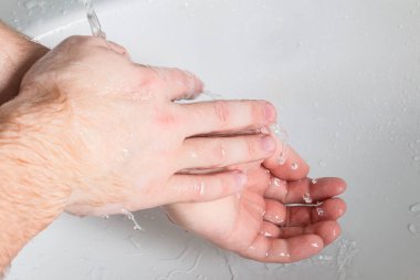 Adam su altında sabun ve ellerini yıkıyor. Hijyen konsepti el detayı.